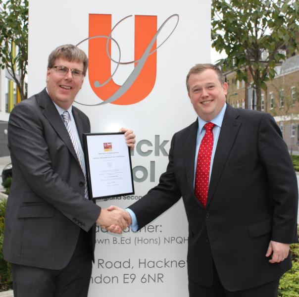 Head teacher Richard Brown receives the certificate from Gareth Harrison